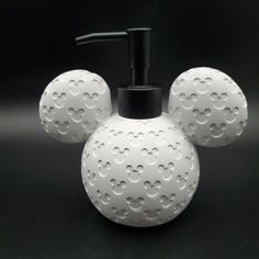 a soap dispenser with three white balls on it and a black top