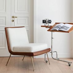 a white chair sitting next to a table with an open book on top of it