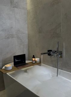 a bathtub with a laptop on it and some candles in front of the tub