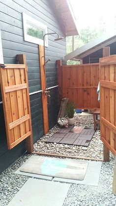 an outdoor shower area with rocks and gravel in the ground next to a wooden fence