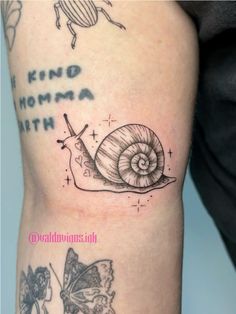 a snail and butterfly tattoo on the right arm, with words written in black ink