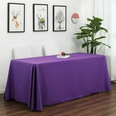 the table is covered with purple cloths and has pictures on the wall behind it