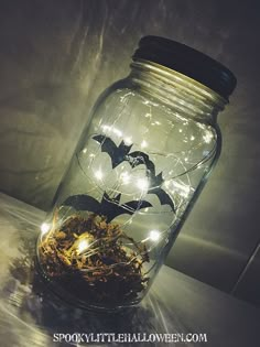 a glass jar filled with lights and bats on top of a white tablecloth covered surface