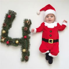 a baby is laying next to the letter h with christmas decorations on it's feet