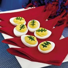 four deviled eggs decorated with green and white footballs on them are sitting next to an orange football