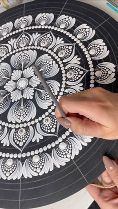 someone is using scissors to cut out an intricate design on a paper plate with black and white paint