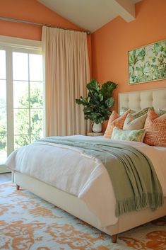 a bedroom with orange walls and white bedding, large window overlooking the trees in the distance