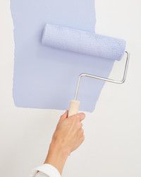 a person holding a paint roller in their hand and painting the wall with blue color