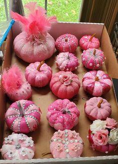 a box filled with lots of pink pumpkins covered in glitter and flowers on top of a window sill