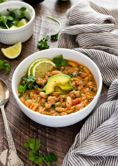 a white bowl filled with beans and avocado on top of a wooden table