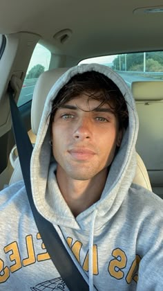 a man sitting in the back seat of a car wearing a hoodie and looking at the camera