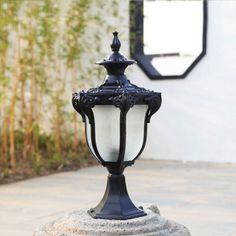 an old fashioned street light sitting on top of a cement block