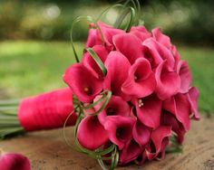 a bouquet of pink flowers sitting on top of a wooden table next to green grass