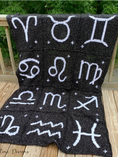 a black blanket with white writing on it sitting on top of a wooden deck next to trees