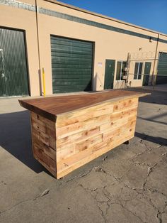 a large wooden counter sitting in front of a storage building with closed doors on both sides