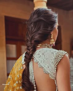 a woman with long hair wearing a yellow sari and gold jewelry on her neck