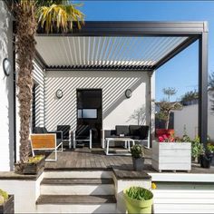 an outdoor patio with chairs and plants on the deck area, under a pergolated roof