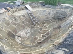 a ladder is sitting on top of an old stone wall that has been built into the ground