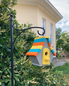 a birdhouse hanging from a pole in front of a house