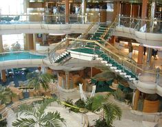 an indoor swimming pool on the deck of a cruise ship with stairs and palm trees