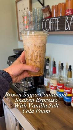 a person holding up a drink in front of a counter