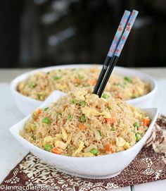 two bowls filled with rice and vegetables on top of a place mat next to chopsticks