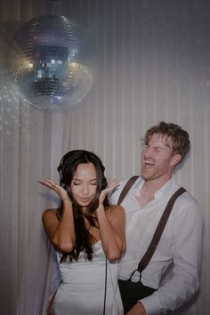 a man standing next to a woman in front of a disco ball