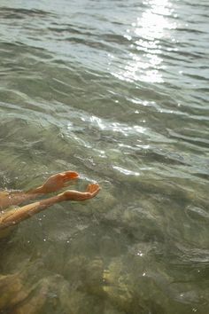 a person floating in the water with their feet up and one hand on his hip