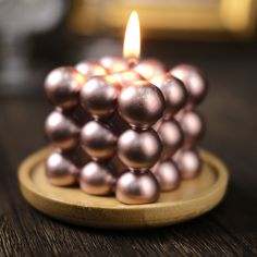 a close up of a candle on a wooden plate with some balls around it and a lit candle in the middle