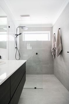 a bathroom with a walk in shower next to a white counter top under a window