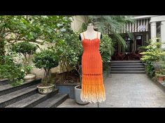 an orange dress is on display in front of some plants