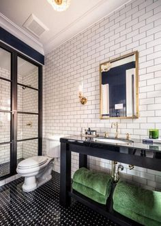 a black and white tiled bathroom with green towels