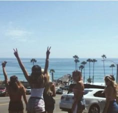 four girls are standing in the street with their arms up and one girl is holding her hands up