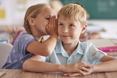 two children sitting at a table with their hands on their faces