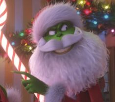 the grinch is holding a candy cane in front of christmas lights and garlands