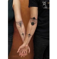 two people holding hands with tattoos on their arms