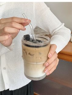 a woman is holding a drink with a straw in her hand