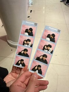 two people holding up polaroid pictures in front of a white tiled floored room