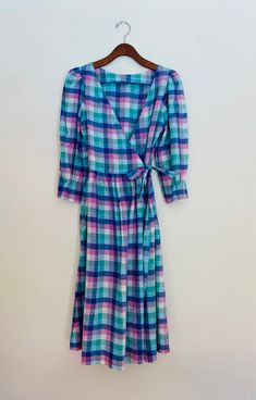 Vintage madras check wrap dress size 4. Fit and flare with A-line skirt bottom hitting below the knee. V neckline and capulet sleeve. Sleeves are 3/4 length with pleated effect at cuff. Fabric ties at waist that weave through insert holes to wrap and tie for closure. Two side insert pockets. Brand is Mati Sport. Believe it to be from the late 70s/early 80s. Measures 43.5 inches length and 17 in from underarm to underarm. 100% cotton. Made in India. Dress Clothes For Women, A Line Skirt, A Line Skirts, Fit And Flare, Wrap Dress, Art Collection, A Line, Dress Outfits, Bathing Beauties