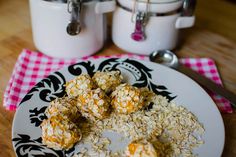 a white plate topped with oatmeal covered balls next to two jars and spoons