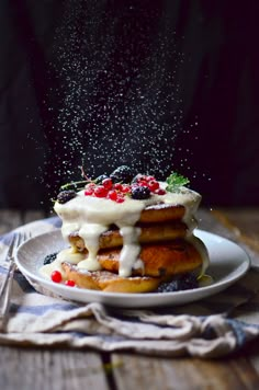 a stack of pancakes covered in icing and berries on top of a white plate