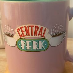 a pink coffee mug with the words central perk painted on it's side