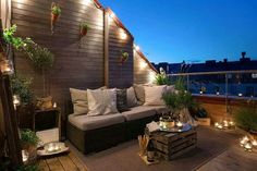 an outdoor living area with couches, tables and potted plants on the wall