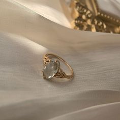 a gold ring with an aqua blue topazte sits on a white satin surface