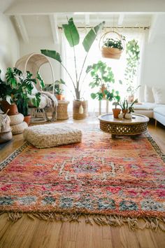 a living room filled with lots of furniture and plants on top of a wooden floor