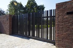 a brick wall and gate with trees in the background