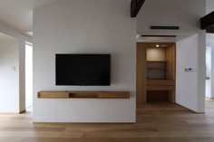 a flat screen tv sitting on top of a wooden shelf in a living room next to a doorway