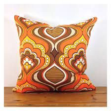 an orange and brown pillow sitting on top of a wooden table