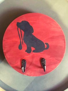 a dog is sitting on top of a red circle with two black hooks in it