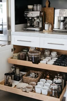 an open drawer in a kitchen filled with pots and pans